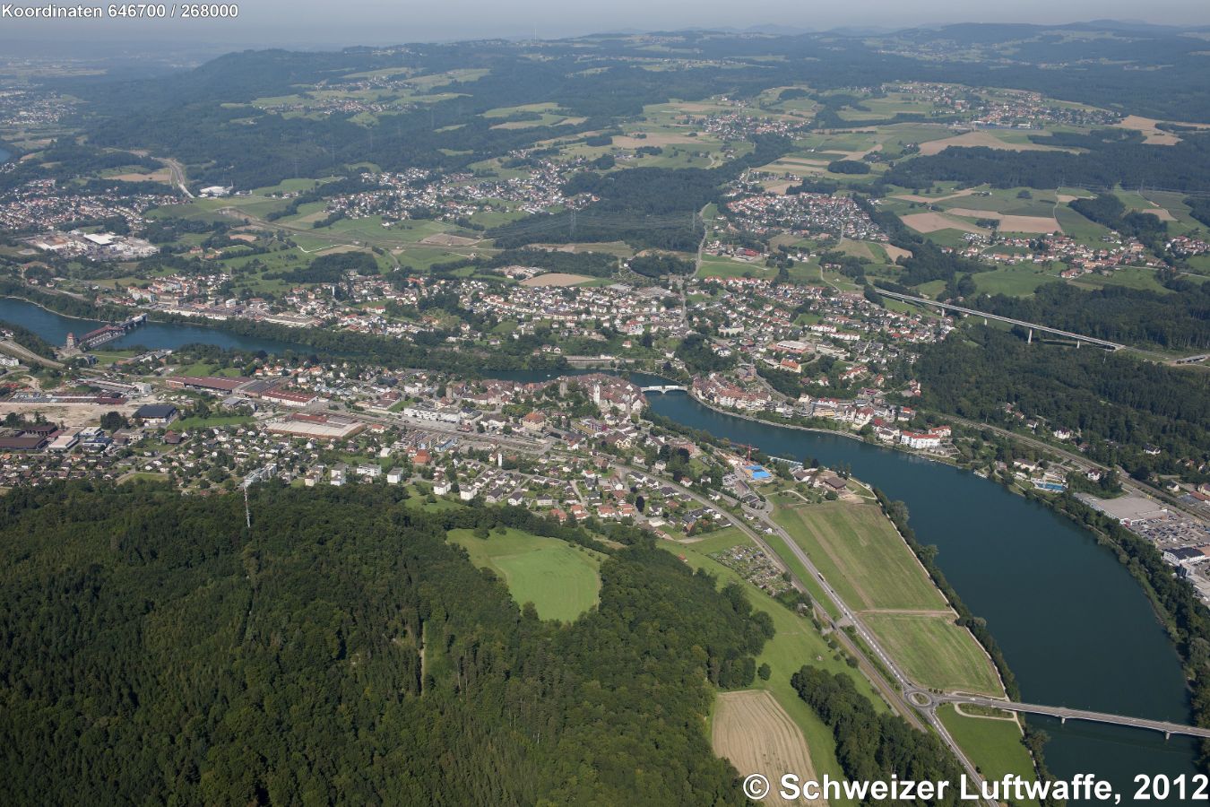 Laufenburg CH (Position:2'646'708.32, 1'268'059.07) im Bildzentrum mit Brücke zu Laufenburg D (Baden). Rheinabwärts am linken Bildrand: Kraftwerk. Rechter Bildrand Mitte: Autobahnbrücke A98, nörlich davon: Siedlung 'Grunholz', gegen den Bildhintergrund rechts: Siedlung 'Hochsal'- Nördlich des Tunneleingangs der A98: Siedlung 'Binzgen'. NW des deutschen Laufenburg westlich des Waldes: 'Diegeringen'.